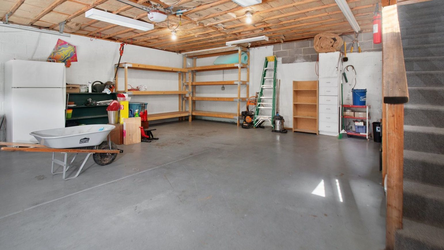 A cleared garage with empty shelving and bare swept concrete from wall to wall