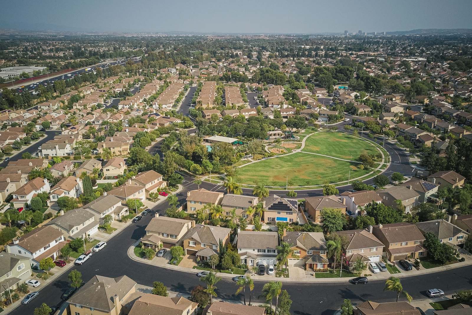 An aerial view of a suburban neighbourhood of the kind NJ Indoor Outdoor serves, houses and tree-lined streets around a green