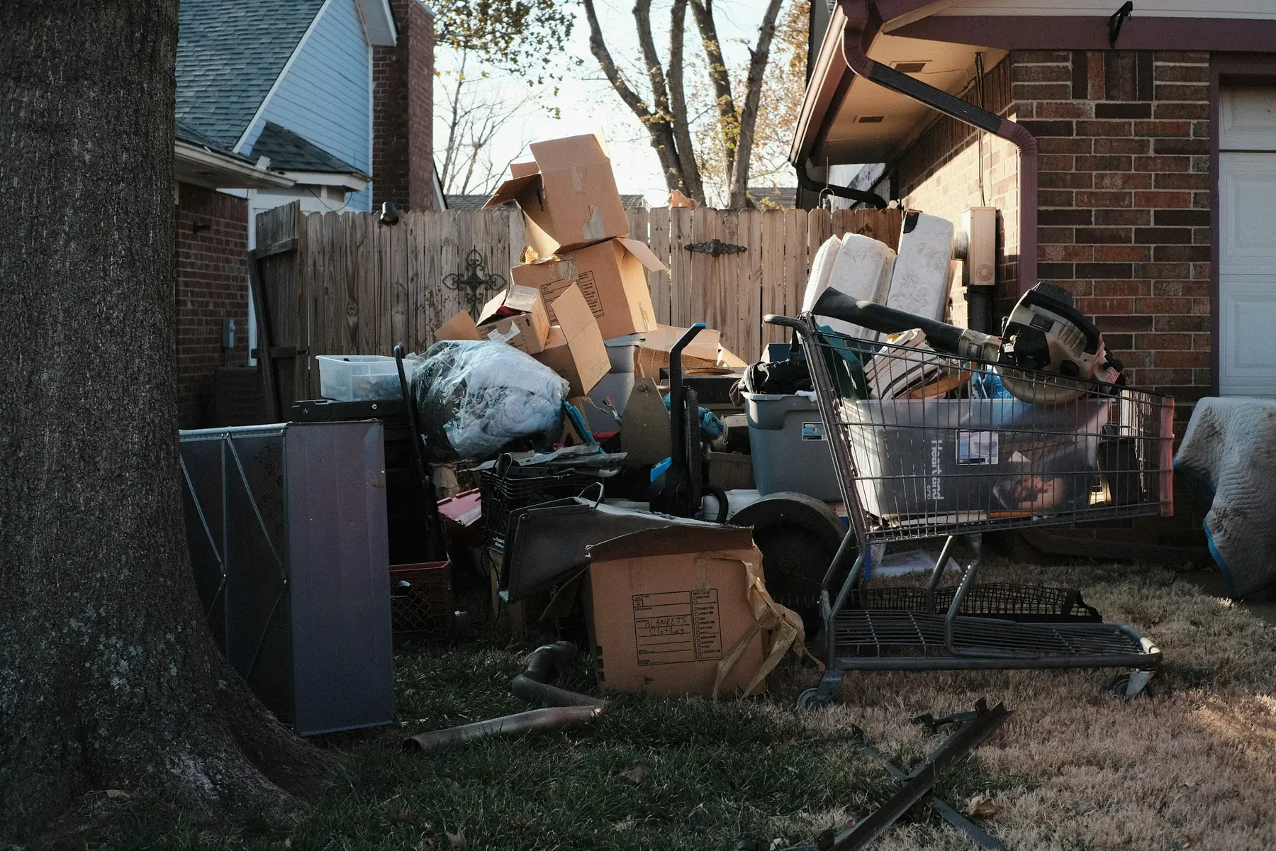 Boxes, furniture, a mattress and other household junk piled on the lawn outside a suburban home, waiting to be hauled away