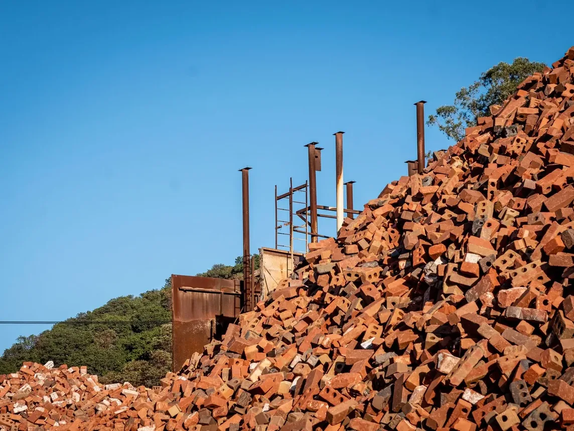 A large pile of broken brick and rubble on a construction site under a clear sky