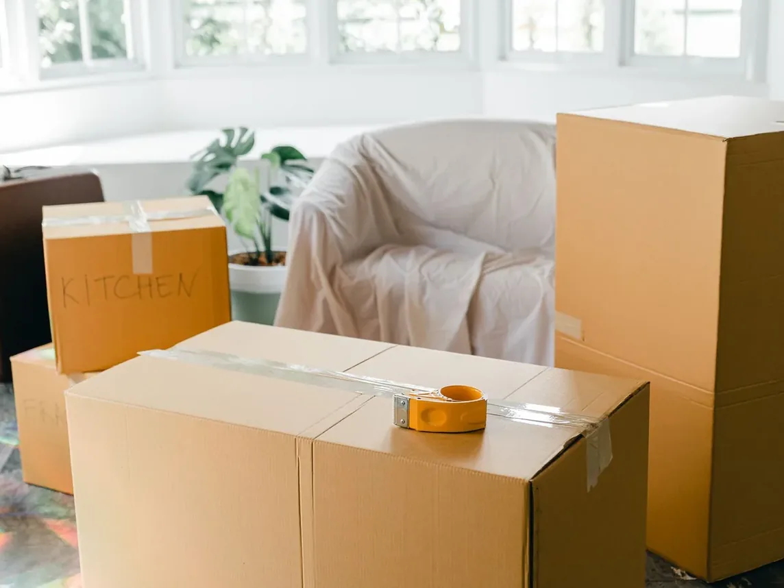 Packed cardboard boxes and sheeted furniture in a room being cleared