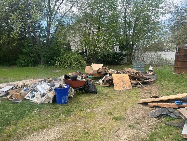 A yard clearance in progress with sorted timber, bins and bagged waste