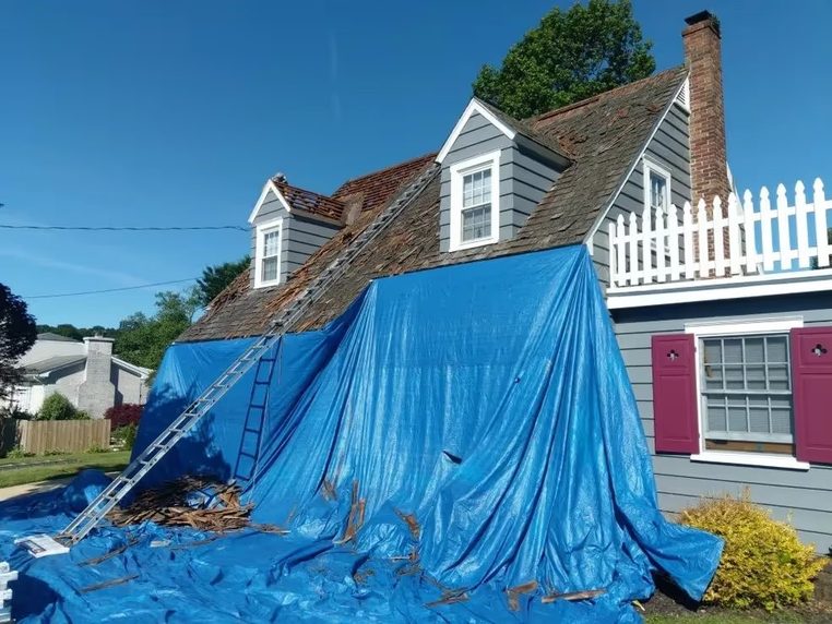 A house roof sheeted with a blue tarp during renovation work